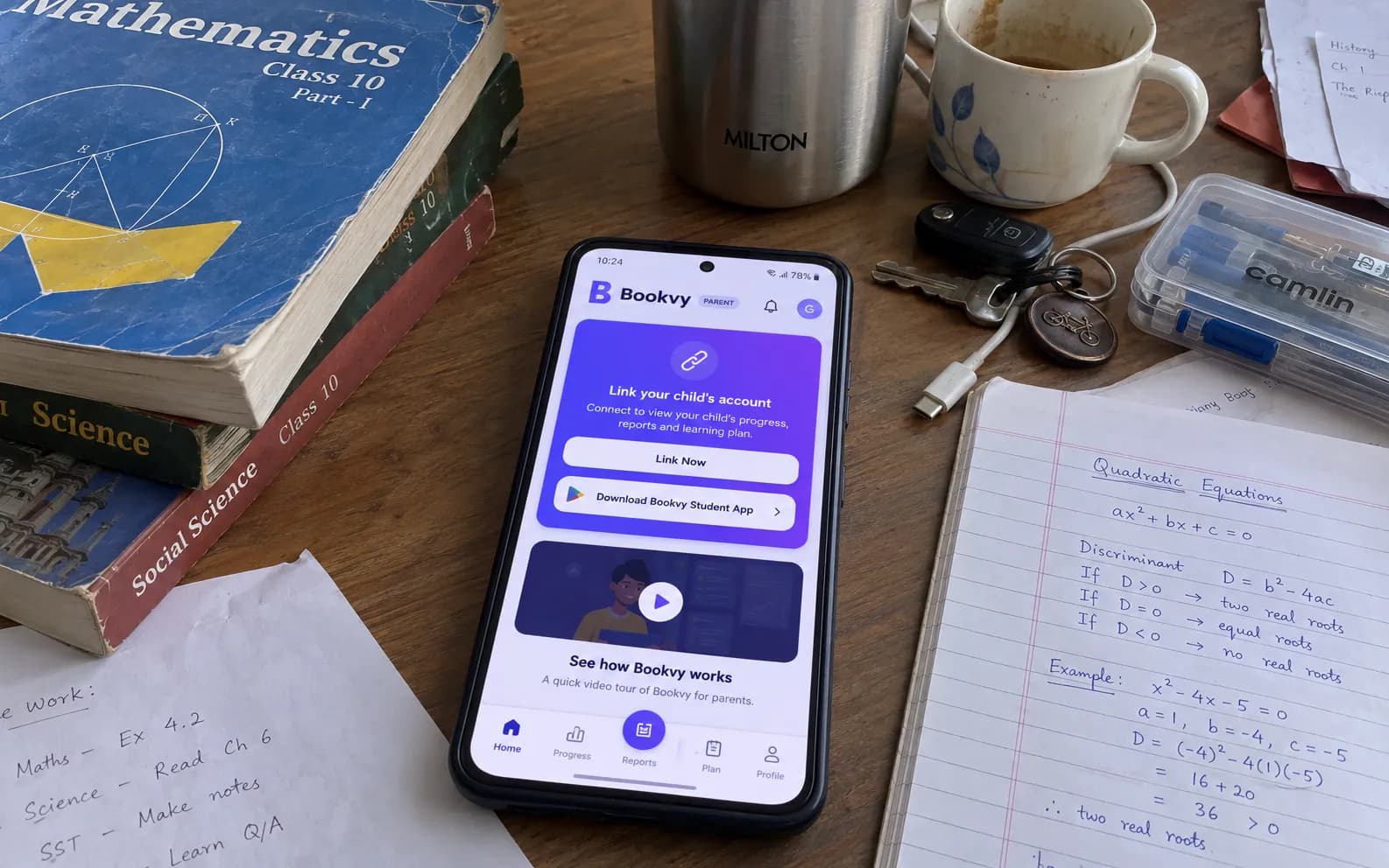 The Bookvy app on a phone on a Class 10 student's desk, next to maths textbooks and handwritten notes